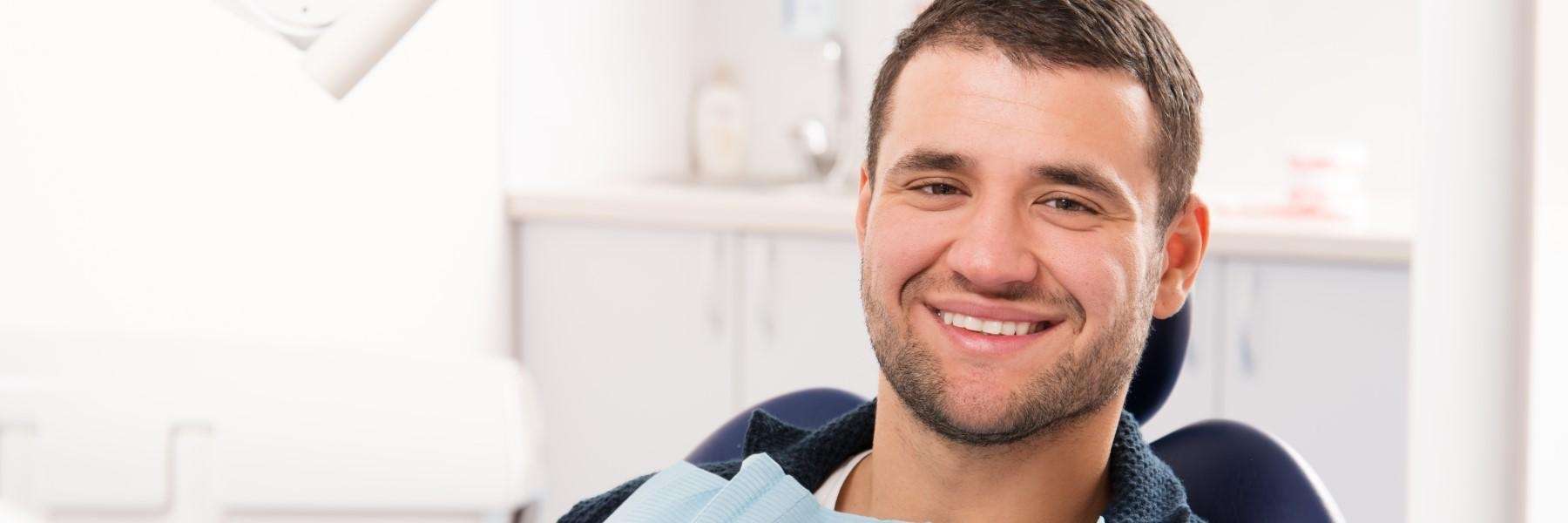 Young man smiling in dentist chair after tooth extraction recovery, Garran ACT